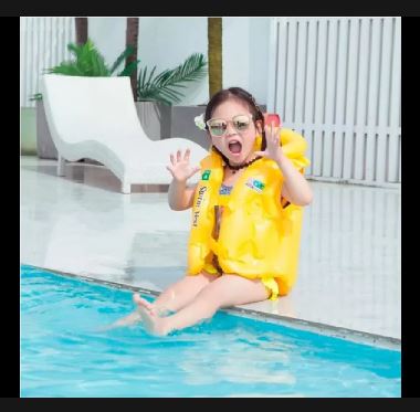 Niña en la piscina con chaleco flotador